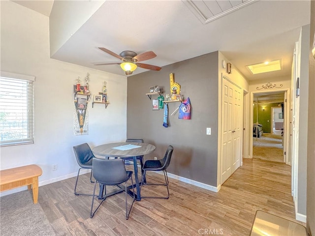 dining area featuring a ceiling fan, light wood-type flooring, and baseboards