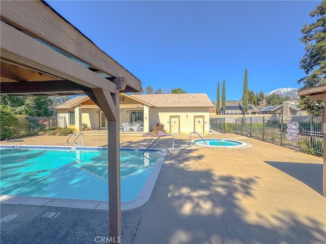 pool with fence, a hot tub, and a patio