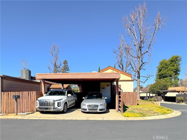 view of vehicle parking with driveway, an attached carport, and fence