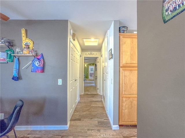 corridor with baseboards and wood finished floors