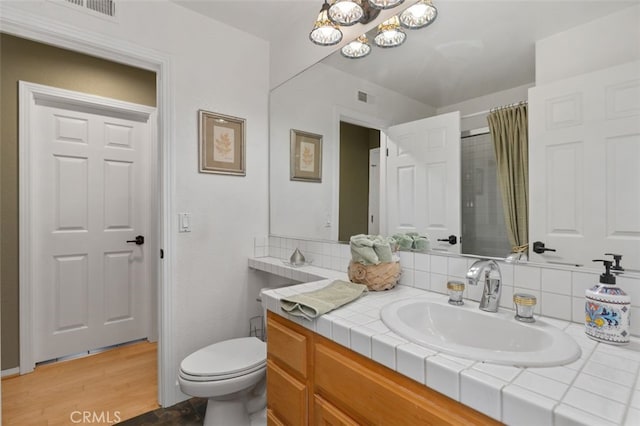 bathroom featuring toilet, vanity, visible vents, and decorative backsplash