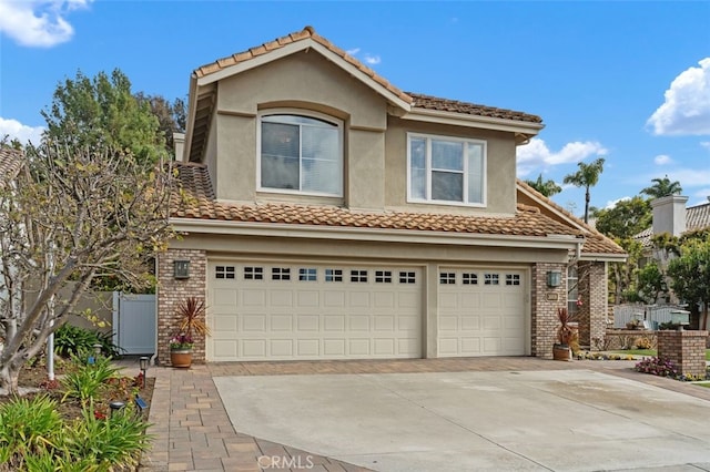 view of front of property with concrete driveway, brick siding, an attached garage, and stucco siding