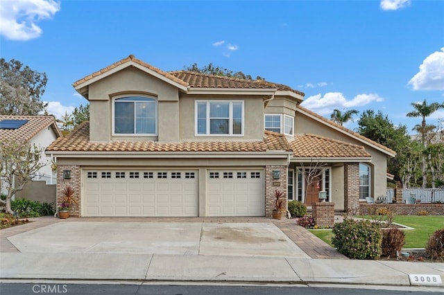 view of front of home featuring an attached garage, a tiled roof, concrete driveway, and stucco siding