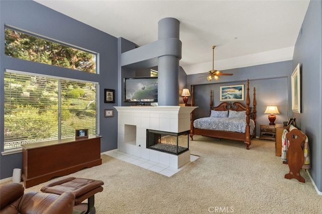 bedroom with light carpet, ceiling fan, baseboards, and a tiled fireplace