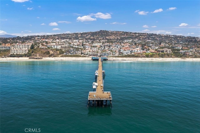 property view of water featuring a dock, a view of the beach, and a city view