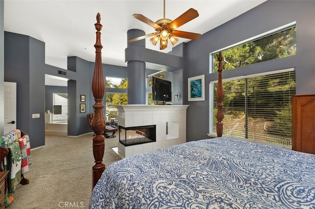 bedroom featuring a tile fireplace, light colored carpet, visible vents, and a high ceiling