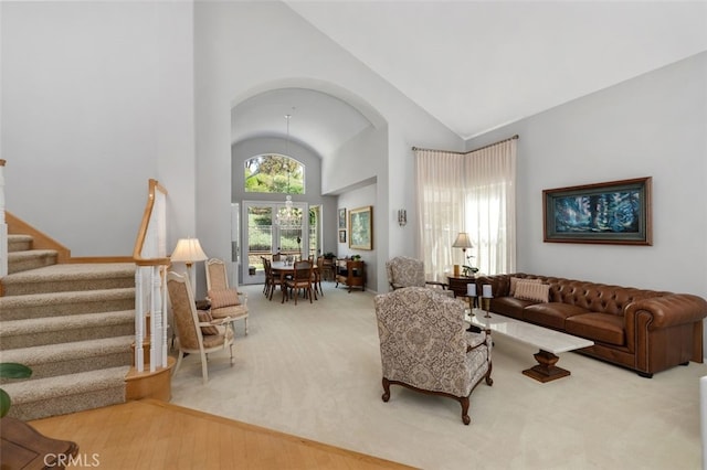 carpeted living room with high vaulted ceiling and stairs