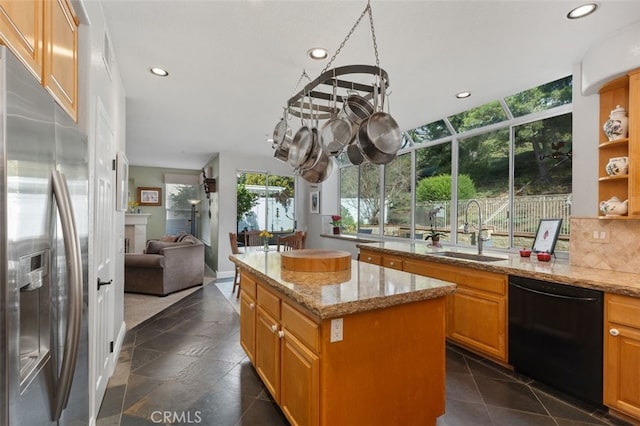 kitchen with light stone counters, a center island, black dishwasher, stainless steel refrigerator with ice dispenser, and a sink