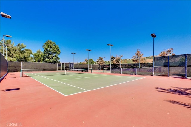 view of tennis court featuring community basketball court and fence