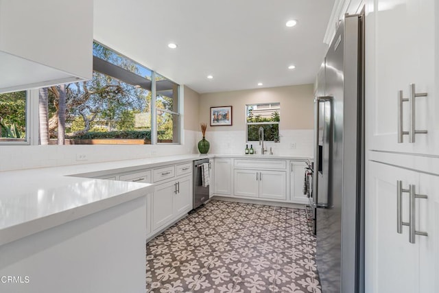 kitchen featuring stainless steel appliances, a sink, white cabinetry, light countertops, and light floors