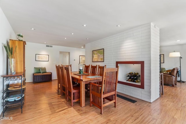 dining room featuring light wood-style floors, recessed lighting, visible vents, and a multi sided fireplace