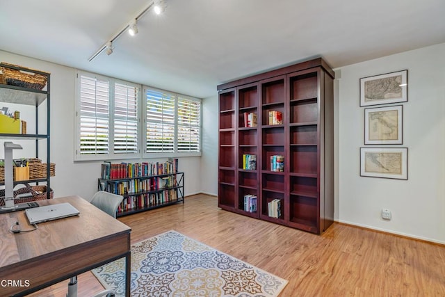 home office with baseboards, rail lighting, and light wood-style floors