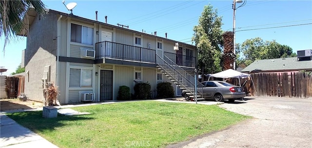 view of front facade featuring stairs, fence, and a front lawn