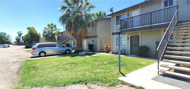 view of property with stairs and uncovered parking