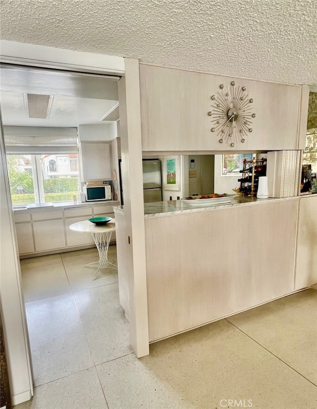 300 S Patencio Rd, Palm Springs, CA 92262 - kitchen featuring freestanding refrigerator, speckle patterned floor, a textured ceiling, and white microwave