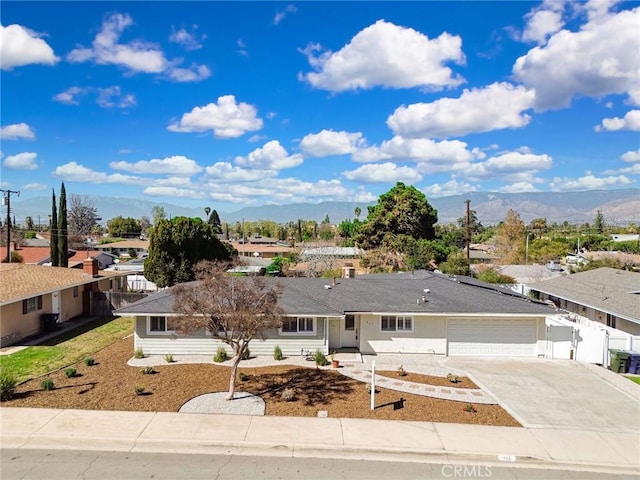 ranch-style home with concrete driveway, an attached garage, a mountain view, fence, and a residential view