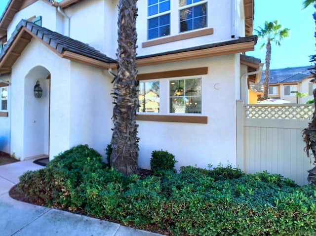 view of side of property with fence and stucco siding