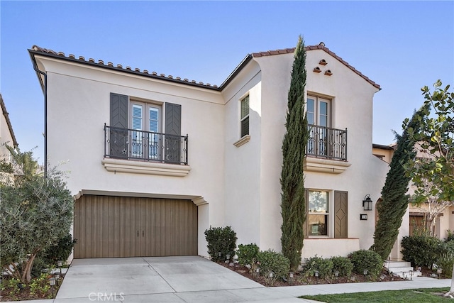 mediterranean / spanish house featuring a balcony, driveway, a garage, and stucco siding