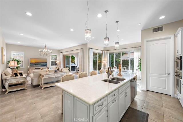 kitchen with a center island with sink, open floor plan, light countertops, white cabinetry, and a sink