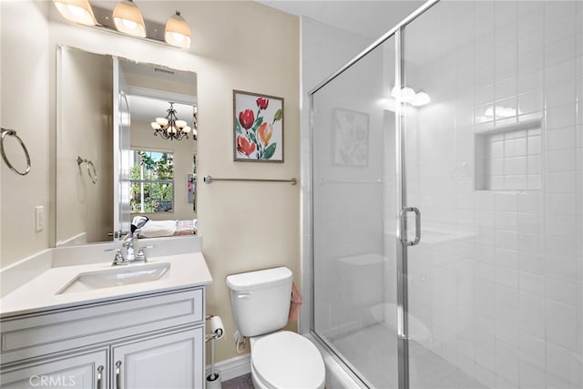 ensuite bathroom featuring a stall shower, toilet, ensuite bathroom, vanity, and a notable chandelier