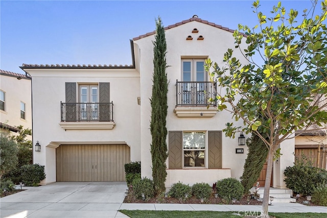 mediterranean / spanish house with driveway, a balcony, and stucco siding