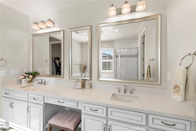 bathroom with double vanity, a shower stall, and a sink