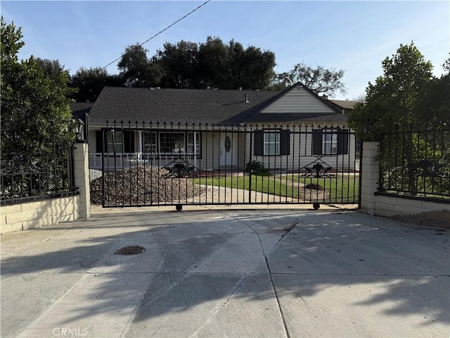 view of front of house featuring a fenced front yard, a gate, and a shingled roof