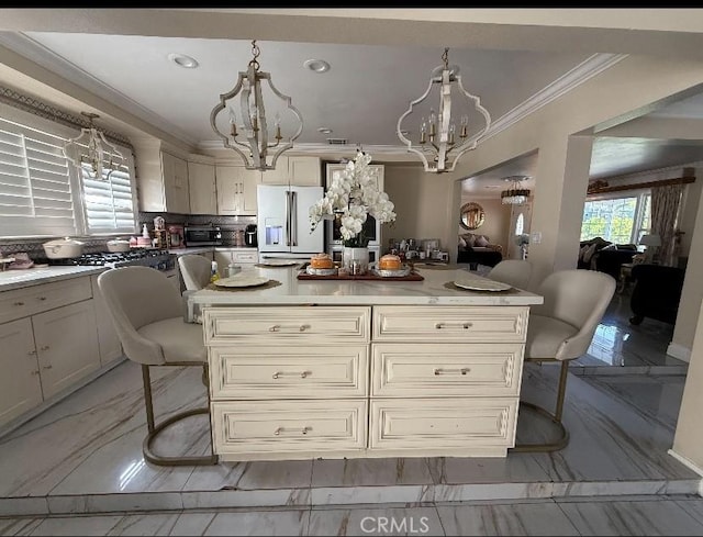 kitchen with a chandelier, white refrigerator with ice dispenser, a kitchen breakfast bar, light countertops, and hanging light fixtures