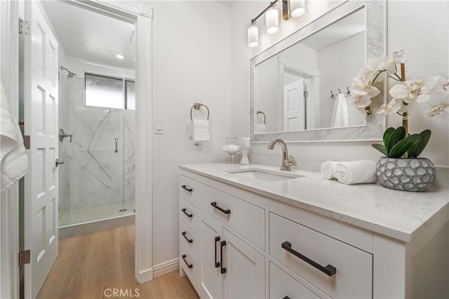 full bathroom featuring vanity, a marble finish shower, and wood finished floors