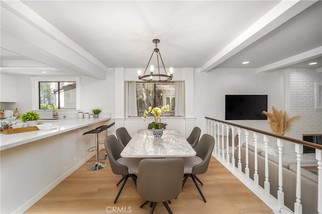 dining room with light wood finished floors, a notable chandelier, beamed ceiling, and recessed lighting