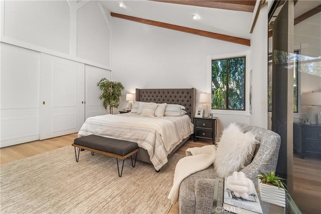 bedroom with vaulted ceiling with beams, a closet, and wood finished floors