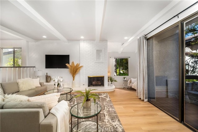 living room with recessed lighting, light wood-style floors, a brick fireplace, beamed ceiling, and baseboards