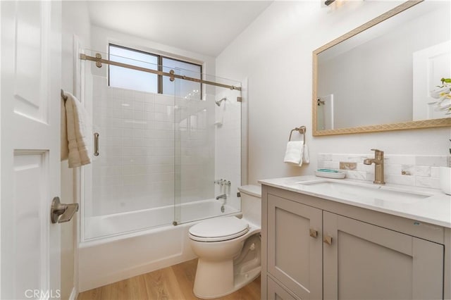 full bathroom with enclosed tub / shower combo, vanity, wood finished floors, and toilet