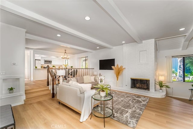 living room featuring light wood finished floors, a fireplace, and beam ceiling