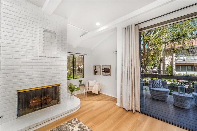 sitting room with vaulted ceiling with beams, a brick fireplace, wood finished floors, and baseboards