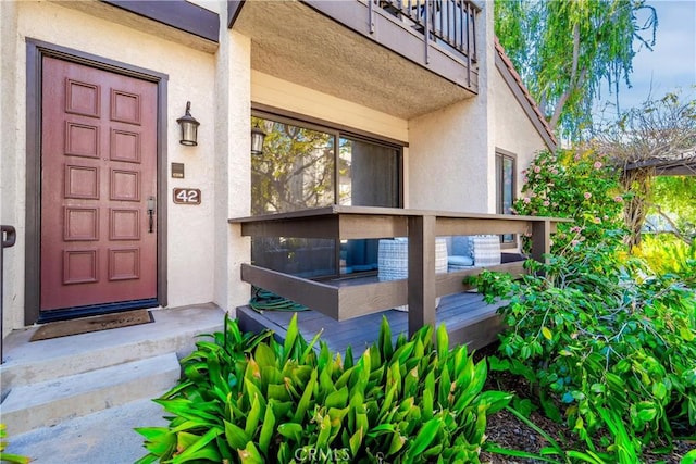 doorway to property featuring a balcony and stucco siding