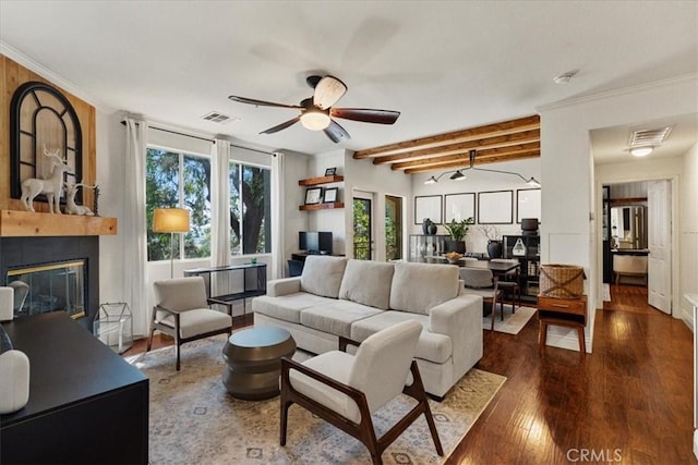 living room featuring wood finished floors, a glass covered fireplace, visible vents, and crown molding