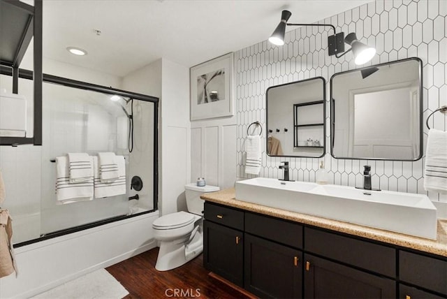 full bathroom with toilet, enclosed tub / shower combo, wood finished floors, vanity, and tile walls