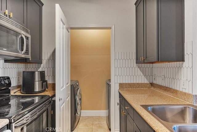 kitchen with light tile patterned floors, electric range, decorative backsplash, stainless steel microwave, and washing machine and clothes dryer