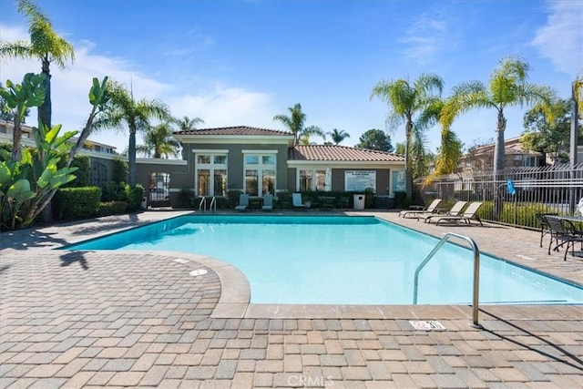 community pool with a patio and fence