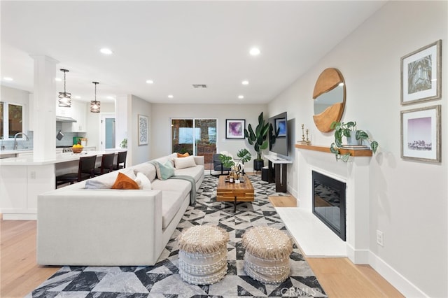 living room featuring a glass covered fireplace, light wood finished floors, and recessed lighting