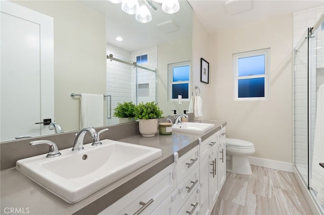 bathroom with a sink, a shower stall, toilet, and double vanity