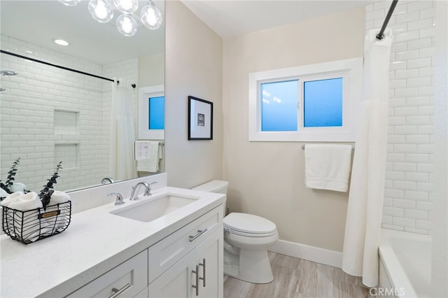 bathroom with baseboards, toilet, wood finished floors, shower / bath combo with shower curtain, and vanity