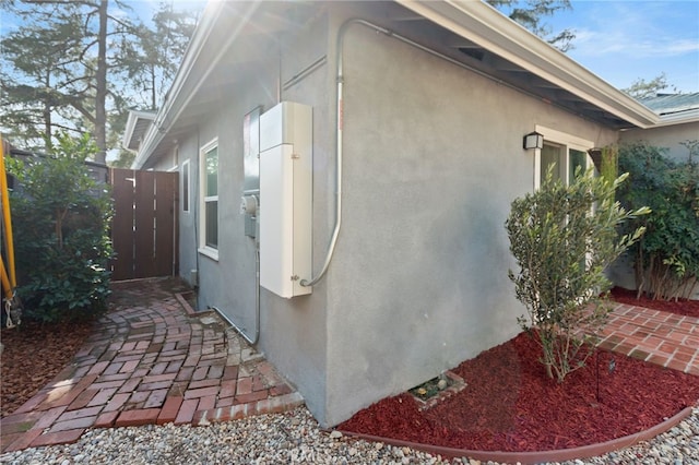 view of side of home with fence and stucco siding