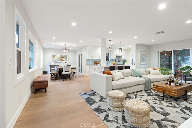 living room with light wood-type flooring, baseboards, visible vents, and recessed lighting