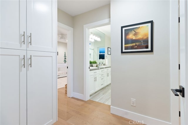 hall with light wood-style floors and baseboards