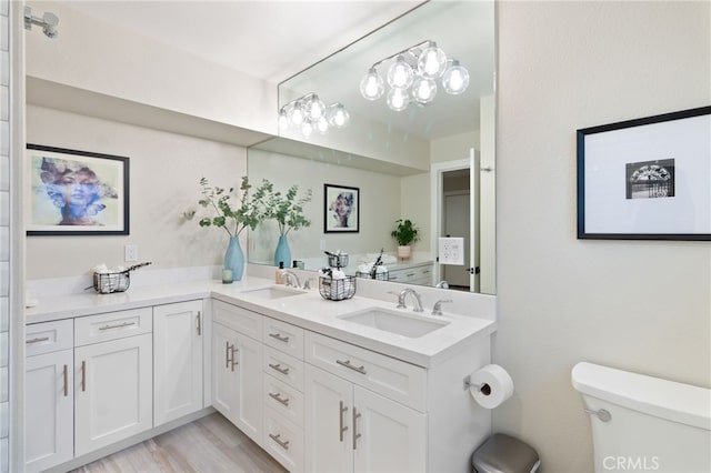 full bathroom featuring double vanity, wood finished floors, a sink, and toilet