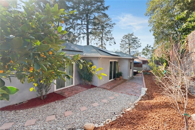 rear view of house featuring a patio, fence, and stucco siding