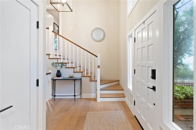 foyer with light wood finished floors, stairway, and baseboards