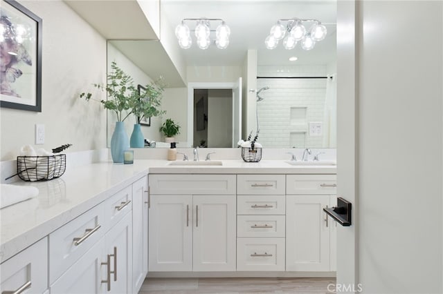 bathroom with a stall shower, a sink, and double vanity